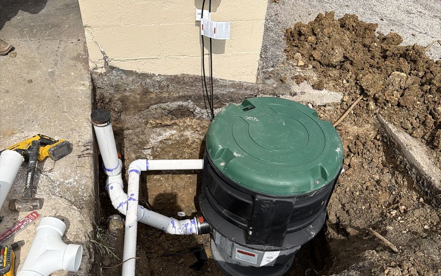 A sewage ejector basin set in the ground and piped in