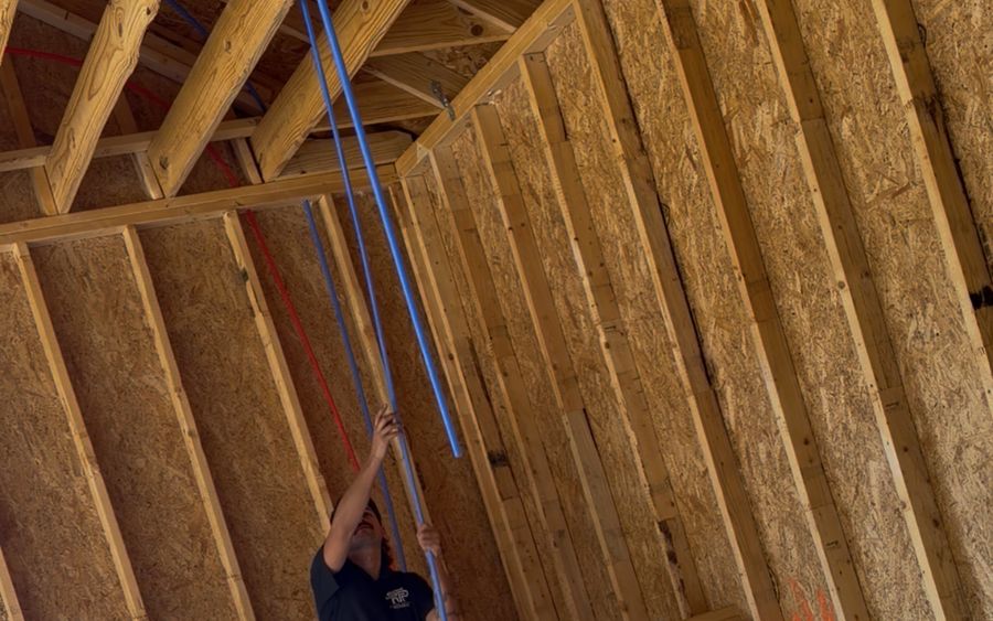 Water lines run up through the ceiling framing of a new house